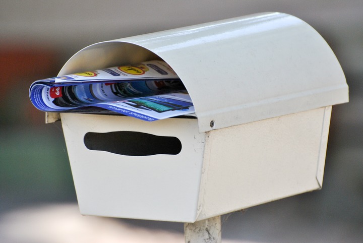 white metal mailbox showing catalog rolled up inside
