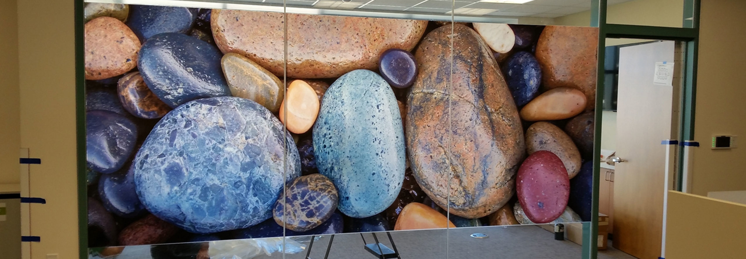 Colorful Translucent Window film featuring photo of wet river stones enlarged and used as privacy film on large interior office window.