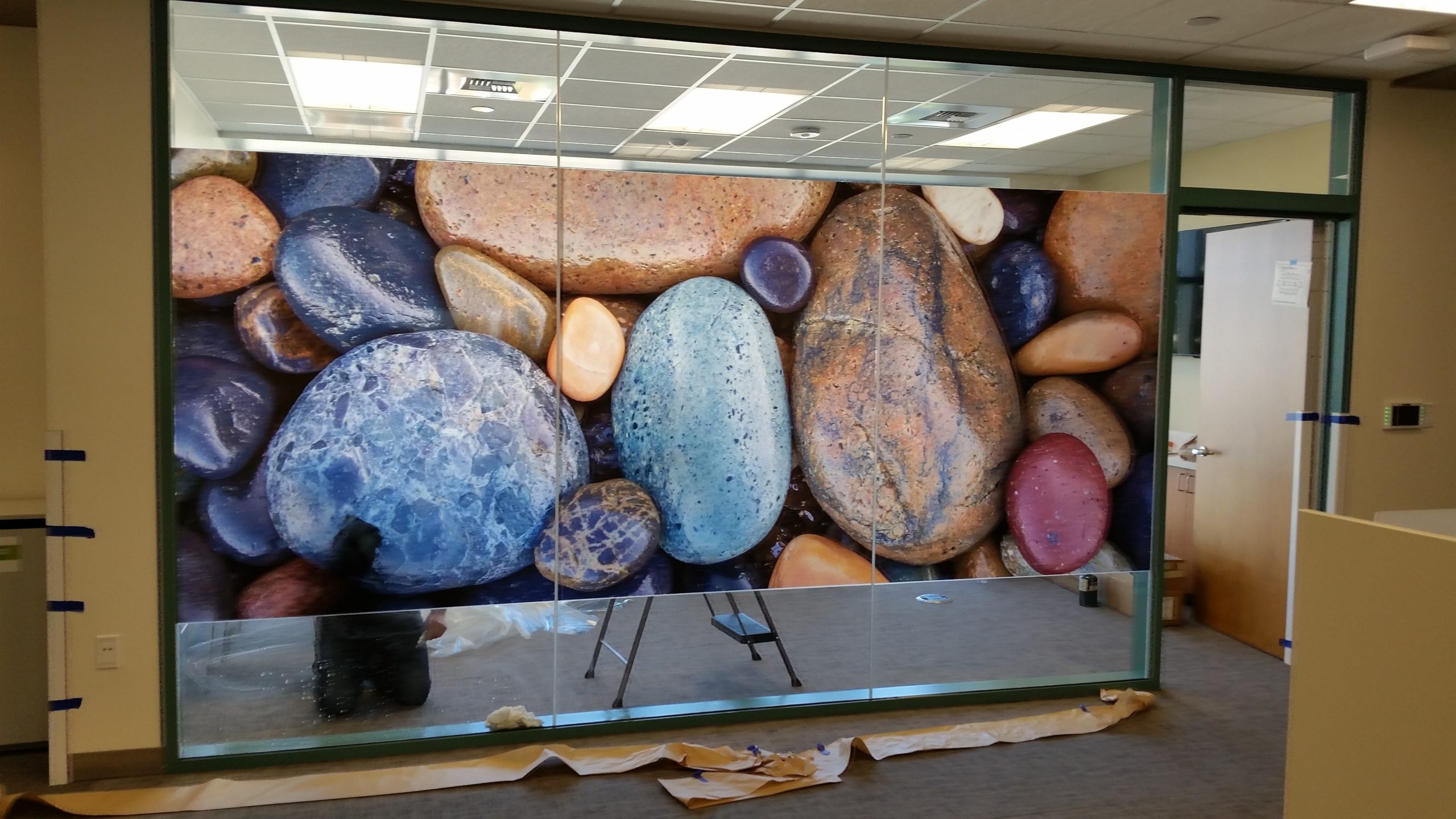 Translucent Window cling close-up of wet river rocks being installed on interior office window for Rady Childrens image from Henry Domke