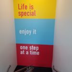 "Life is special. Enjoy it one step at a time" wall mural installation on inner stairway wall behind landing for Mission Fed Credit Union