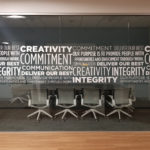 cut white vinyl displaying corporate values in varied thickness fonts on glass viewed head-on
